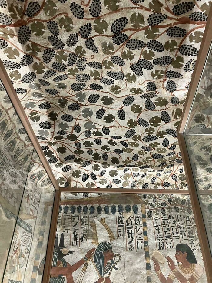Ancient Egypt wall and ceiling paintings featuring hieroglyphs and symbolic figures in a historic tomb chamber.