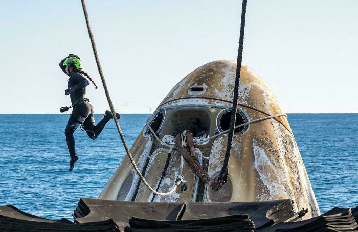 Astronaut in a space suit training with a capsule in the ocean, showcasing unique jobs that make a 9-to-5 more bearable.
