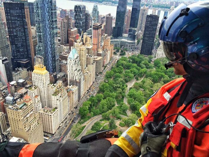 Rescue worker in helmet and safety gear overlooking cityscape and park, showcasing different jobs making 9-to-5 more bearable
