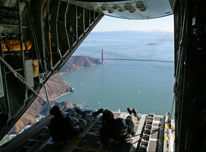 Two people lying in the open cargo bay of a plane overlooking the Golden Gate Bridge, showcasing unique job experiences.