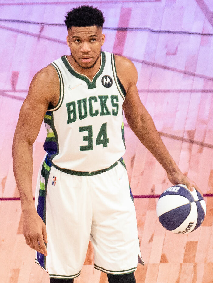 Giannis Antetokounmpo in Milwaukee Bucks uniform during a basketball game, holding a basketball in hand.