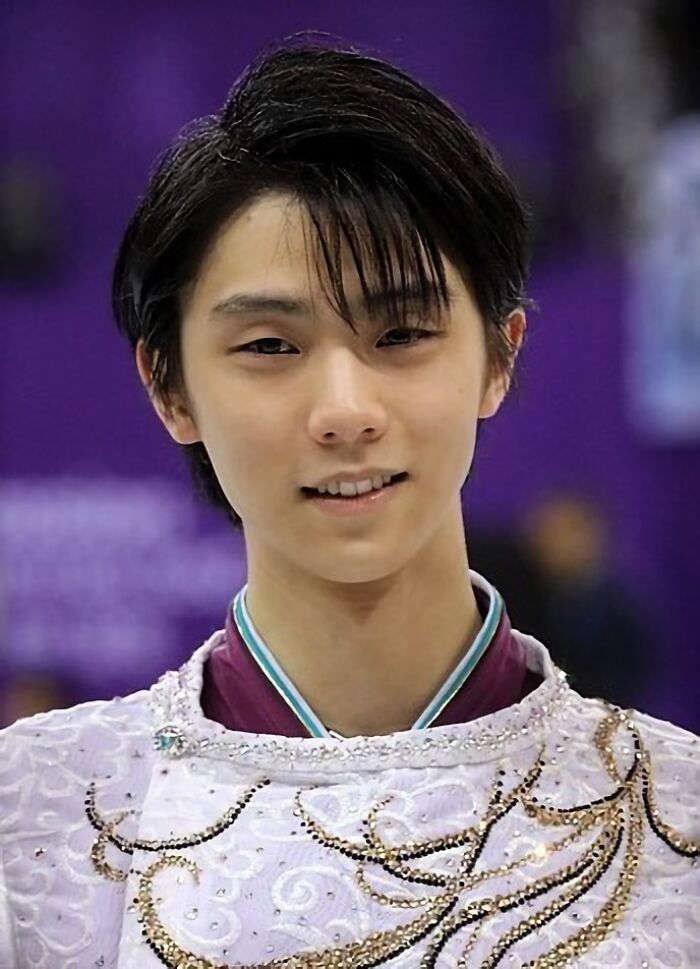 Yuzuru Hanyu smiling in a decorated white costume at a figure skating event, showcasing his career highlights.