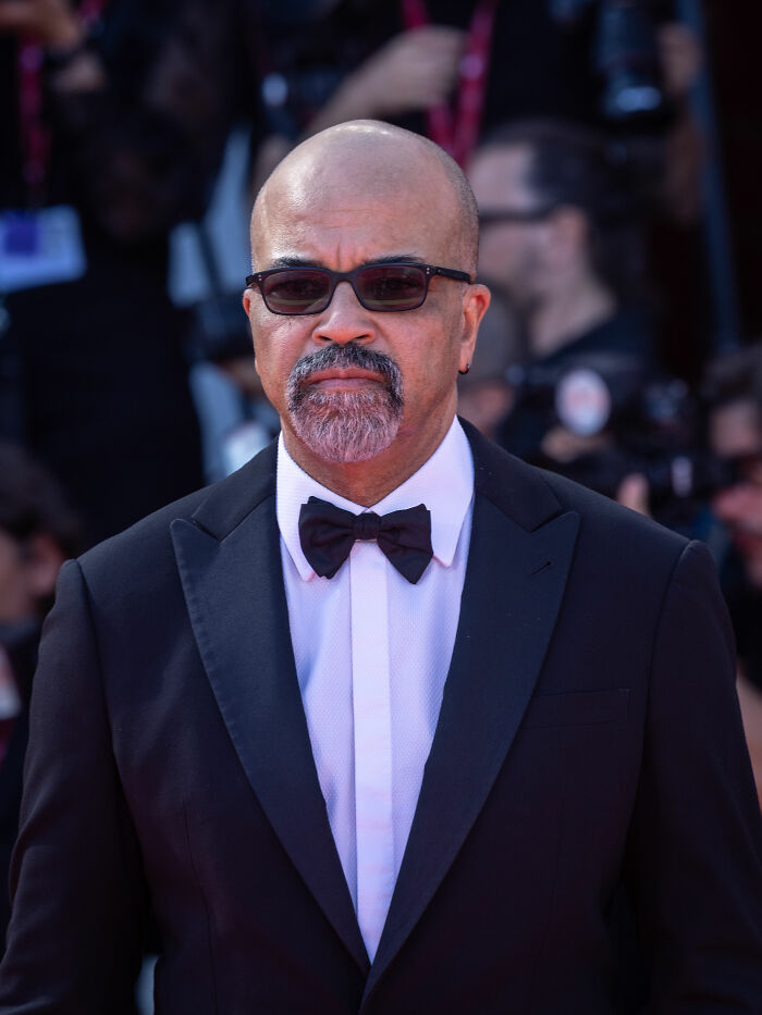 Jeffrey Wright in a black tuxedo and bow tie wearing sunglasses at a formal event with photographers in the background