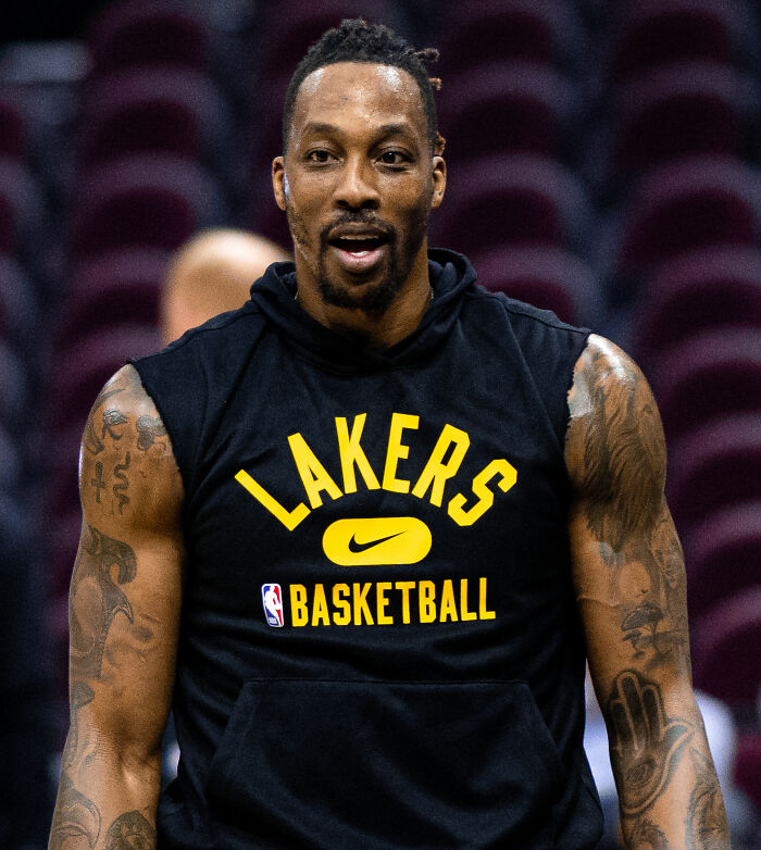 Dwight Howard wearing Lakers basketball sleeveless hoodie during practice, showcasing tattoos and focused expression.