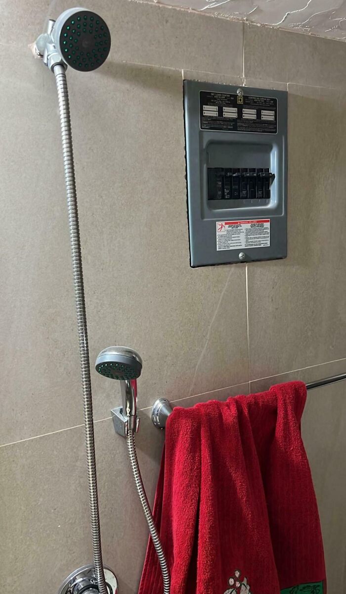 Electrical panel installed dangerously inside a shower area, showcasing employees blatantly ignoring safety protocol risks.