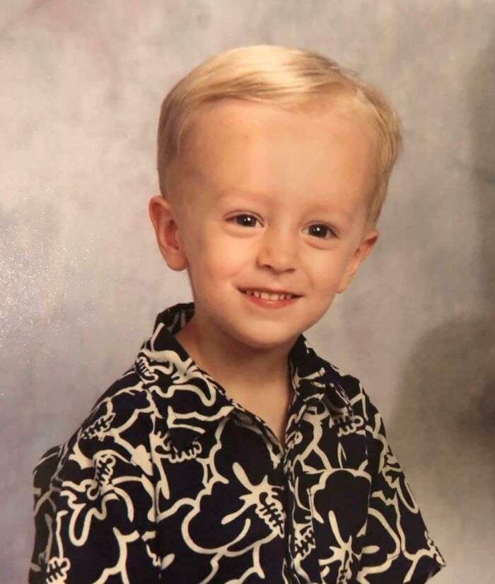 Young boy in a patterned shirt smiling awkwardly in a hilariously awkward childhood photo.