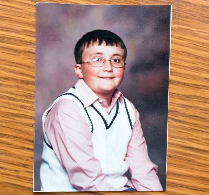 Childhood photo of a boy wearing glasses and a white sweater vest, capturing a hilariously awkward moment.