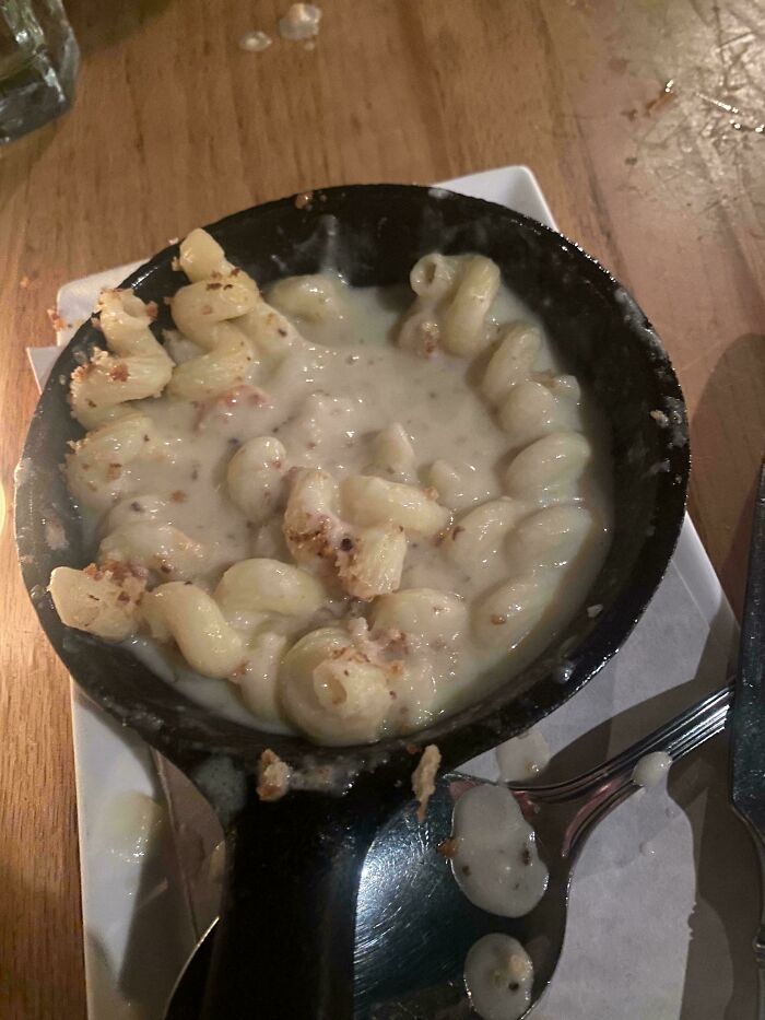 Small skillet of mac and cheese with a creamy sauce and scattered burnt crumbs, showing an outrageous meal fail.