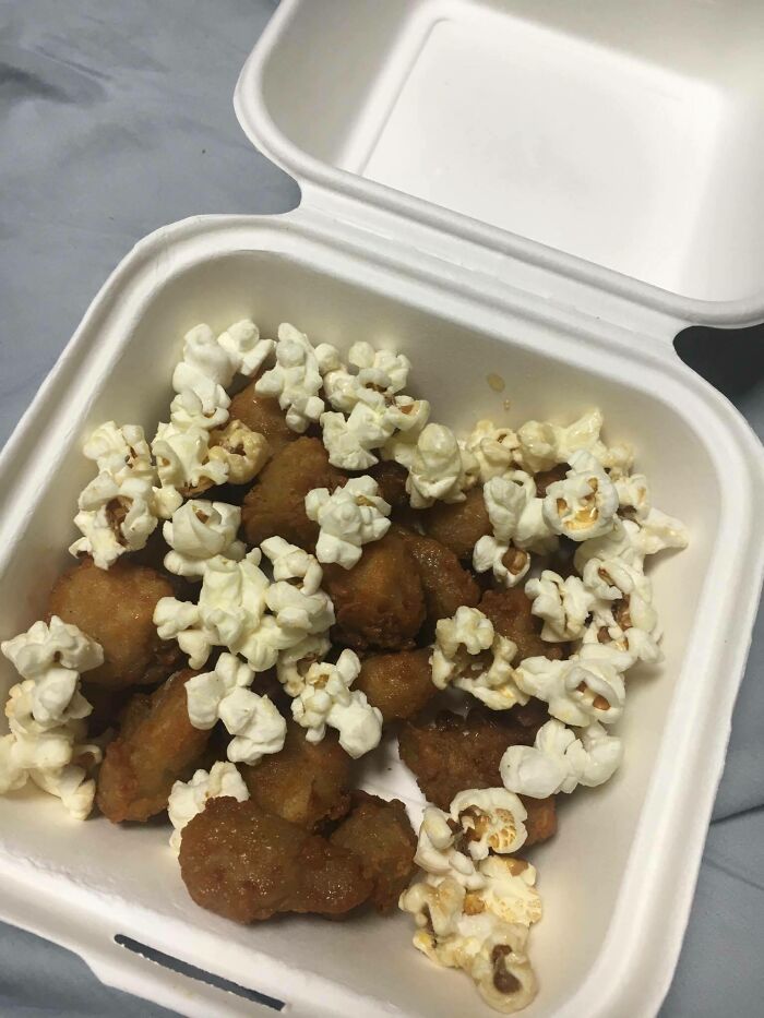 Takeout container with popcorn and fried food pieces, an example of outrageous meals that look nothing like menu photos.