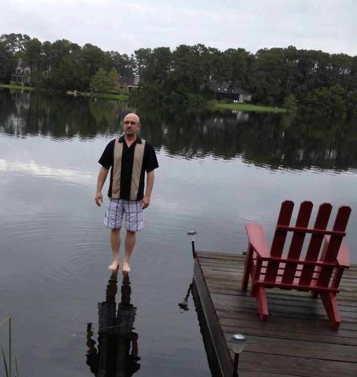 Man appearing to walk on water near dock with red chair in funny, interesting, and weird pics taken at perfect time