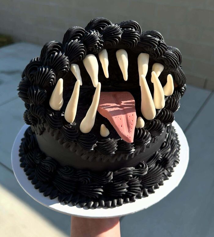 Black and white masterfully crafted cake designed to look like a monster mouth with sharp teeth and a pink tongue.