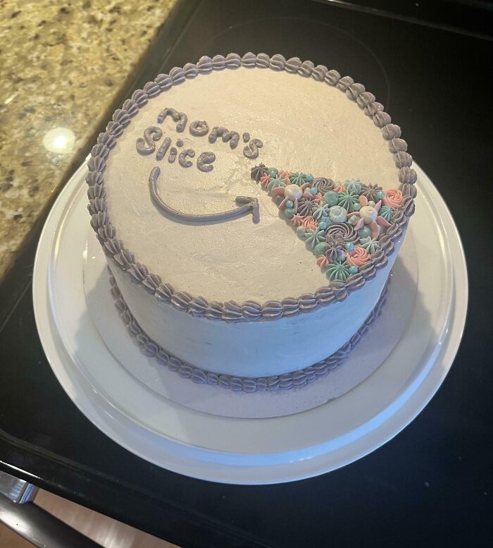 A masterfully crafted cake with white frosting, decorated with pastel floral designs marking one slice as Mom's slice.