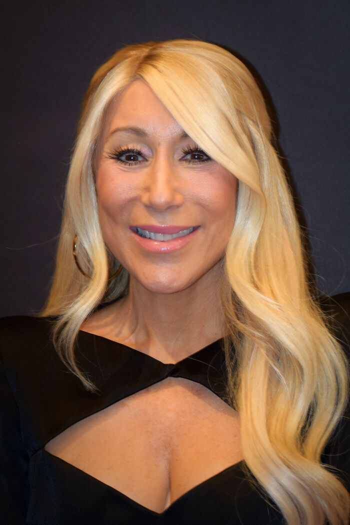 Lori Greiner smiling with long blonde hair, wearing a black outfit, highlighting bio and career achievements.