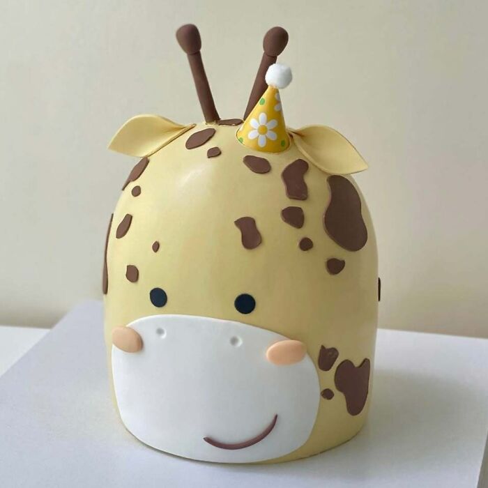Cute giraffe cake with party hat, showcasing masterfully crafted cakes and boundless human creativity in cake design.