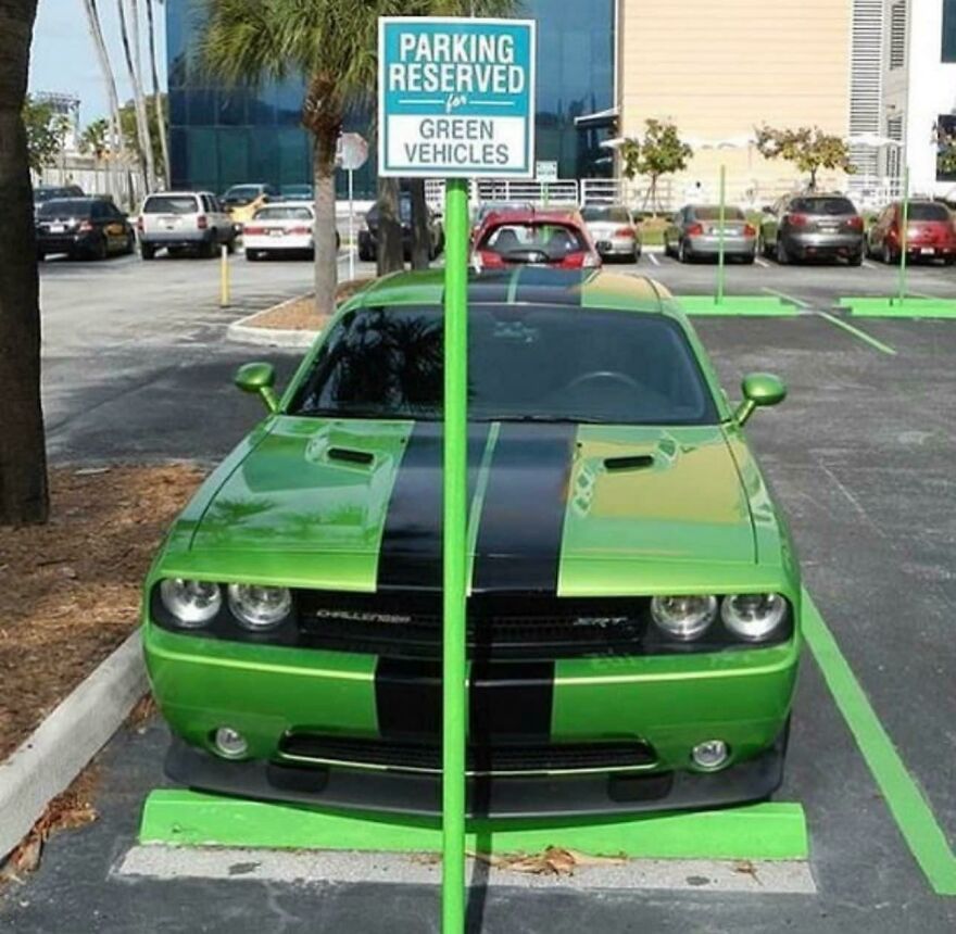 Bright green Dodge Challenger parked in a green vehicle reserved spot, obstructed by a parking sign pole.