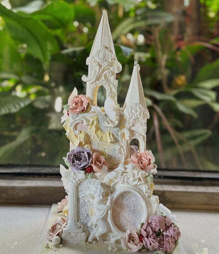 Intricately designed cake resembling a detailed castle with floral decorations showcasing masterful cake creativity.
