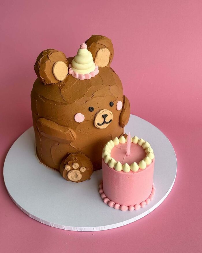 Bear-shaped cake with a small pink frosted cake beside it, showcasing masterfully crafted cakes and creativity.