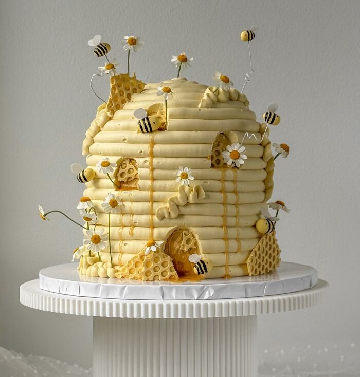 Beehive themed masterfully crafted cake decorated with honeycomb, bees, and flowers showcasing human creativity.
