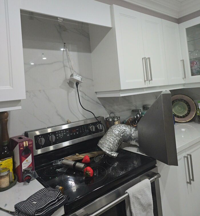 Kitchen stove with a makeshift ventilation duct and exposed wiring showing rental nightmares and landlord corner-cutting mistakes.