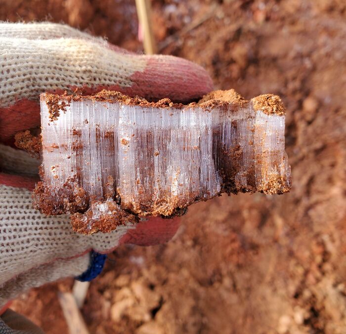 Close-up of a gloved hand holding soil with ice crystals, showcasing unique textures from different jobs that make 9-to-5 more bearable