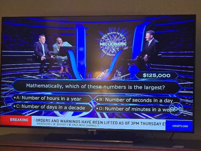 Contestants solving a weird math problem on Who Wants to Be a Millionaire, choosing the largest number option confidently.
