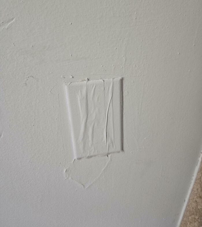 Wall with a poorly patched outlet cover showing a rental nightmare where landlords cut corners on repairs.