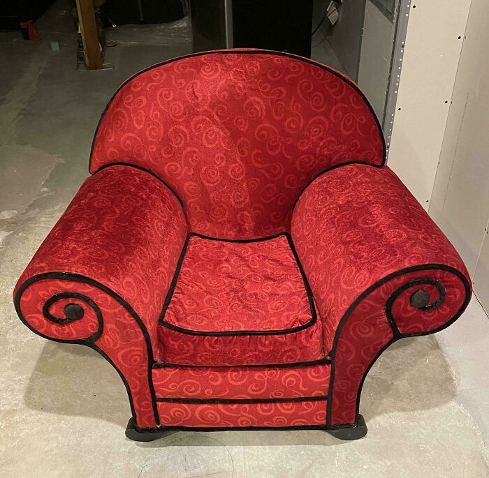 Red vintage-style armchair with black trim found in a secondhand store, showcasing unexpected cool furniture surprise.