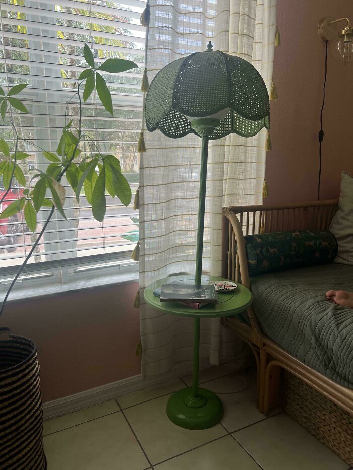 Vintage green floor lamp with built-in table, next to a wicker couch and window, showcasing secondhand store finds.