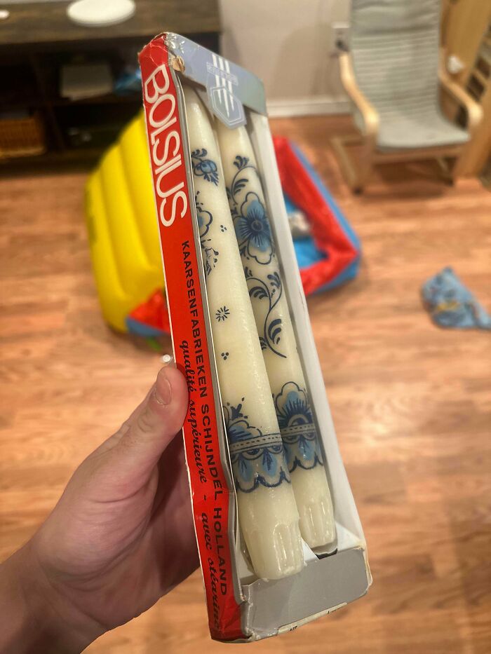 Hand holding a vintage Bolsius candle package with decorative blue floral patterns found at a secondhand store.