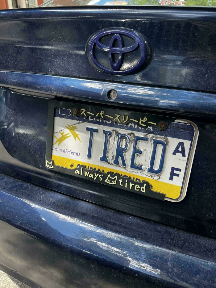 Personalized license plate on a blue Toyota with the word TIRED and a custom frame saying always tired.