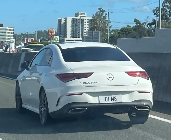 White Mercedes CLA 200 with a personalized license plate 01 M8, captured on a busy urban highway.