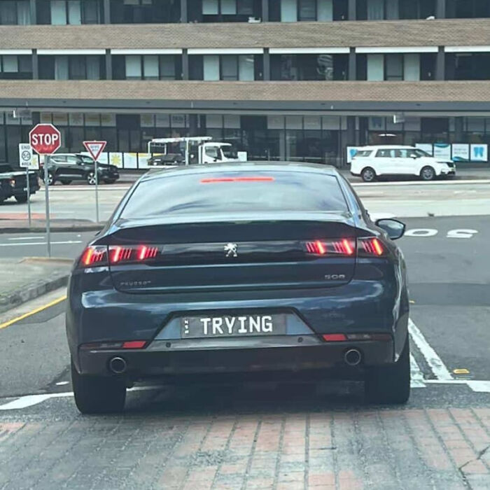 Black Peugeot car with a personalized license plate reading TRYING, part of hilarious personalized license plates collection.