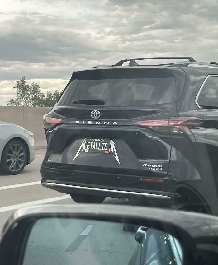 Black Toyota Sienna with a hilarious personalized license plate styled like Metallica logo on a cloudy day on the highway.