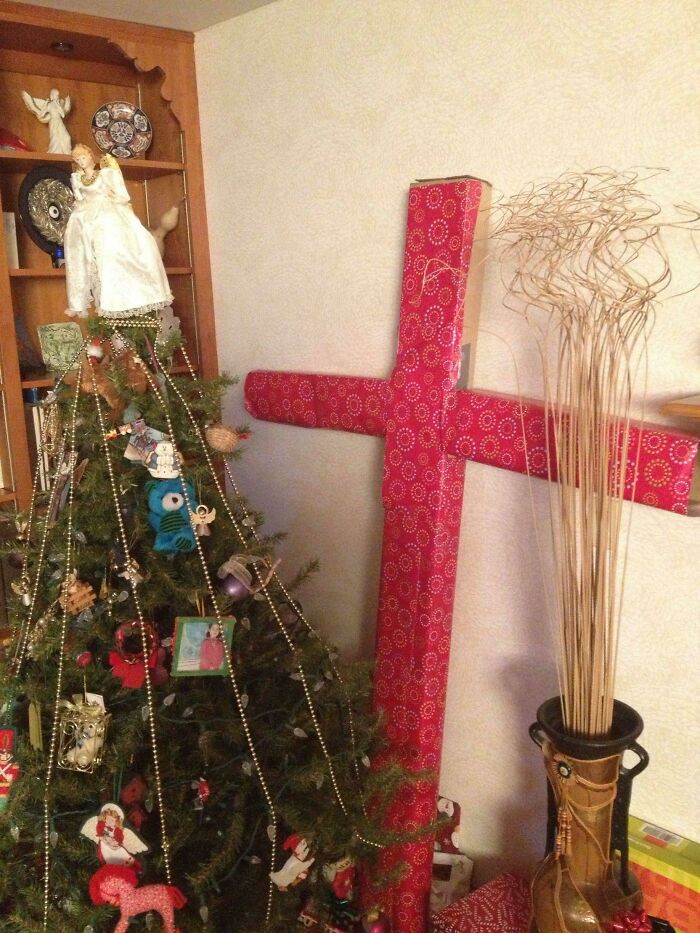 Christmas tree next to a large gift wrap cross with red patterned wrapping paper inspiring funny gift wraps.