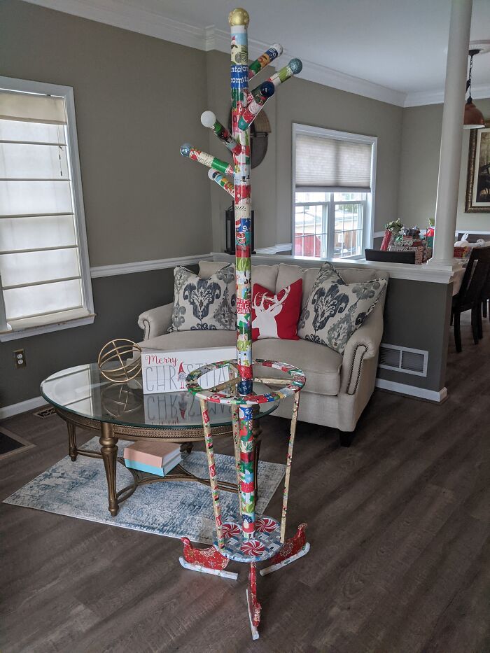 Coat rack creatively covered with funny holiday gift wraps in a cozy living room setting for Christmas mischief inspiration.