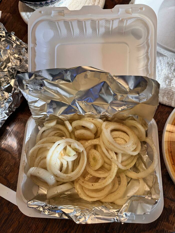 Takeout container with plain raw onion rings, an example of outrageous meals that looked nothing like the menu photos.