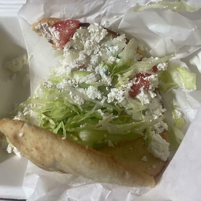 Disappointing meal with lettuce, tomatoes, and cheese on flatbread, showing an outrageous meal that looks nothing like menu photos.