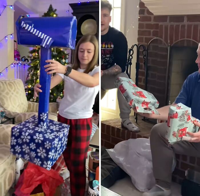 Woman holding giant hammer wrapped in funny Christmas gift wrap while a man opens oddly wrapped presents by fireplace.