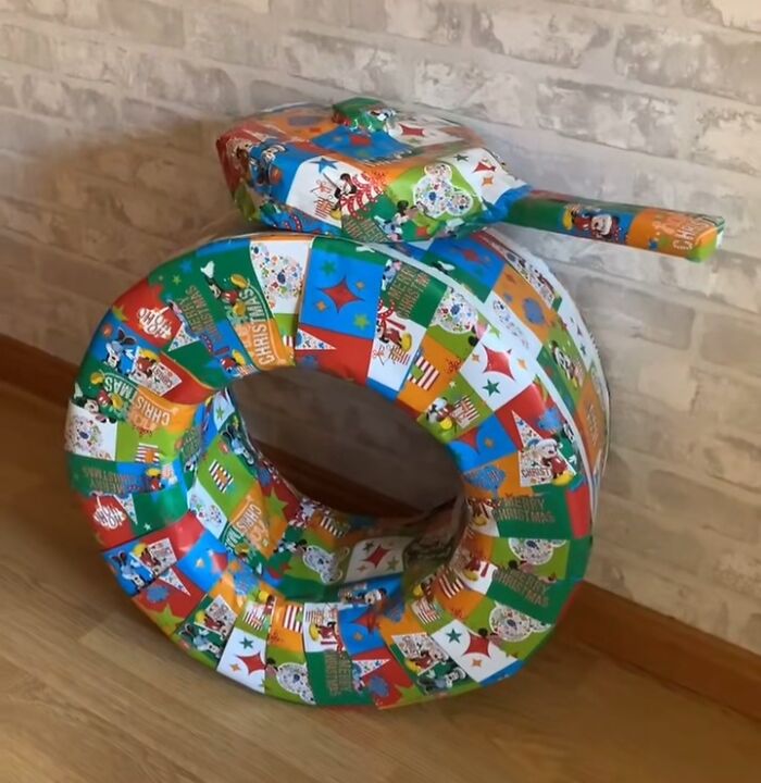 Tire and toy gun wrapped in colorful Christmas gift wrap as a funny and creative holiday gift wrap idea.