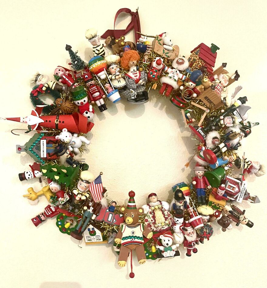 Vintage Christmas decorations wreath made with nostalgic figurines, toys, and holiday-themed miniatures on a wall background.