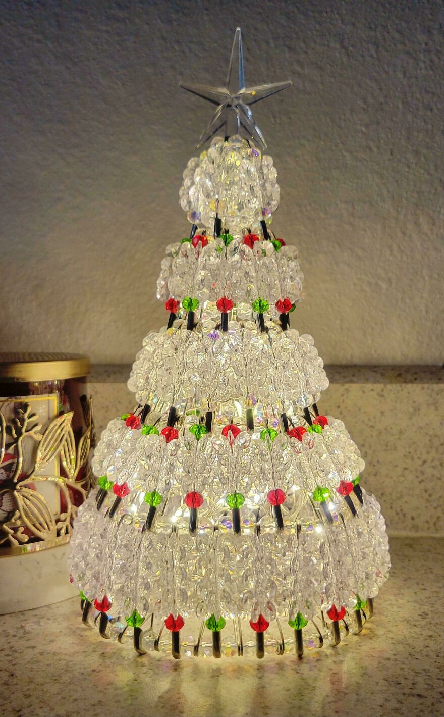 Nostalgic vintage Christmas decorations with a beaded tree featuring red and green accents and a star topper on a countertop.