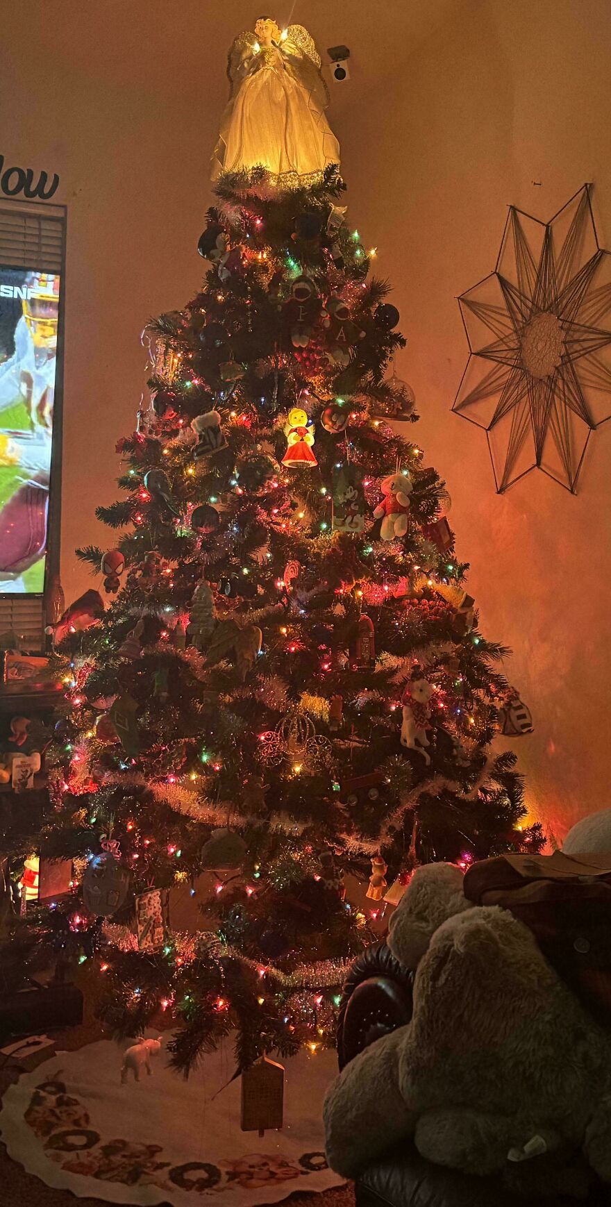 Christmas tree decorated with nostalgic vintage Christmas decorations and colorful lights in a cozy living room setting.