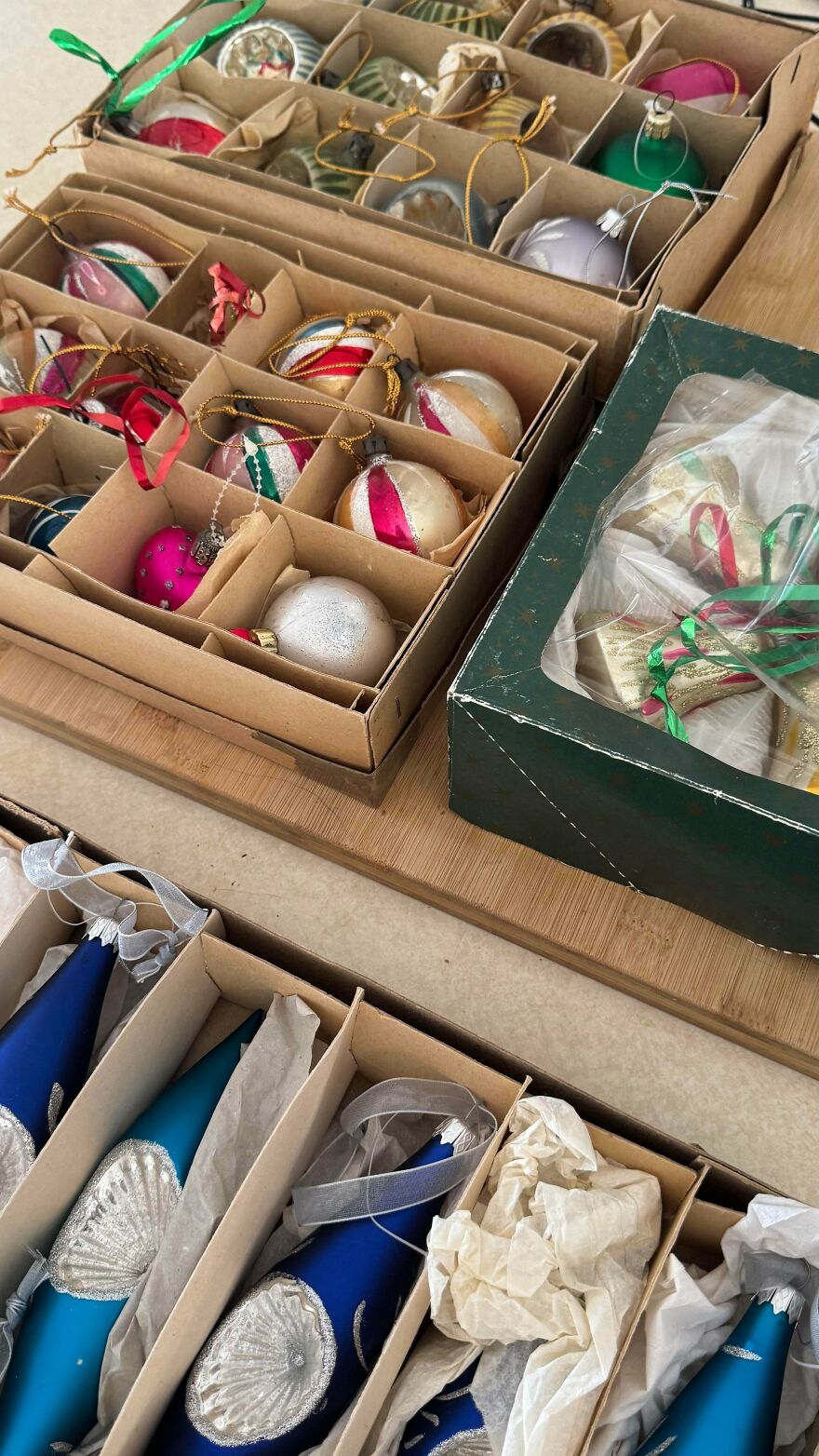 Vintage Christmas decorations including colorful glass ornaments and blue teardrop-shaped baubles stored in cardboard boxes.
