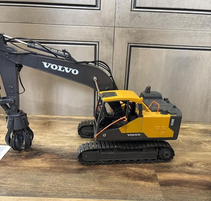 Toy Volvo excavator on wooden floor, a gift idea that unleashes 5-year-old joy and excitement.