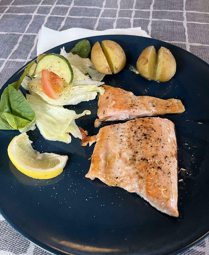 Salmon meal with potatoes, lettuce, cucumber, and lemon slice plated, showing an outrageous meal that looks different than menu photos.