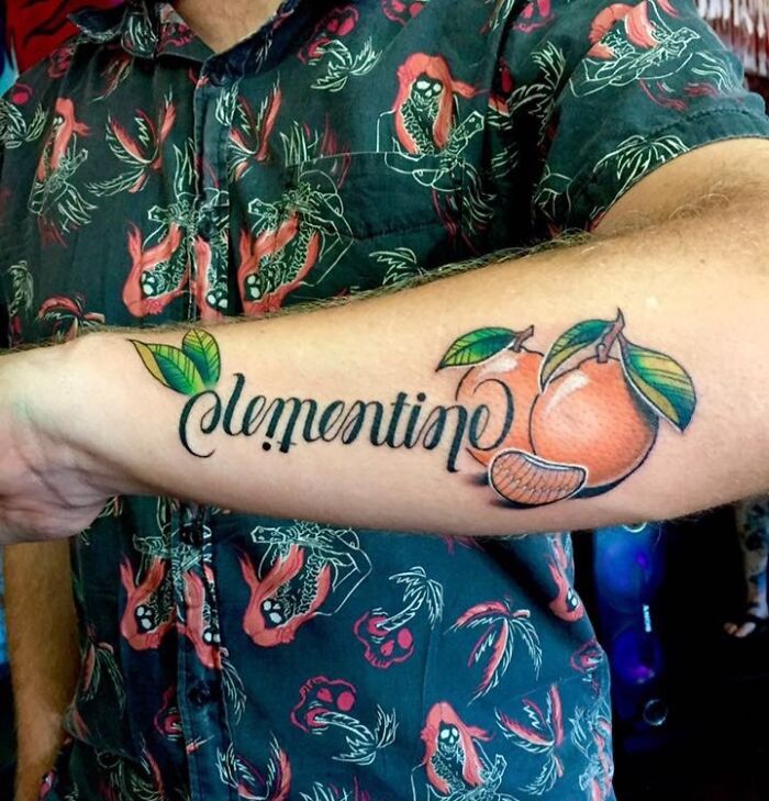 Forearm tattoo of the word clementine with colorful citrus fruit design showcasing wholesome tattoos with meaningful ink.