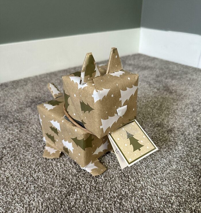 A creative gift wrap shaped like a dog using Christmas tree patterned paper, showcasing funny gift wraps for inspiration.