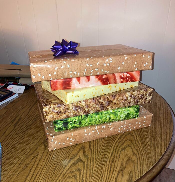 Stack of gifts wrapped in funny gift wraps designed to look like sandwich ingredients for Christmas mischief inspiration.