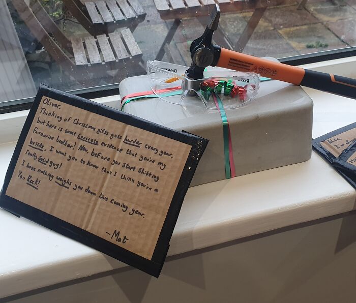 Gift wrapped present with safety glasses, hammer, and funny handwritten note for Christmas mischief inspiration.