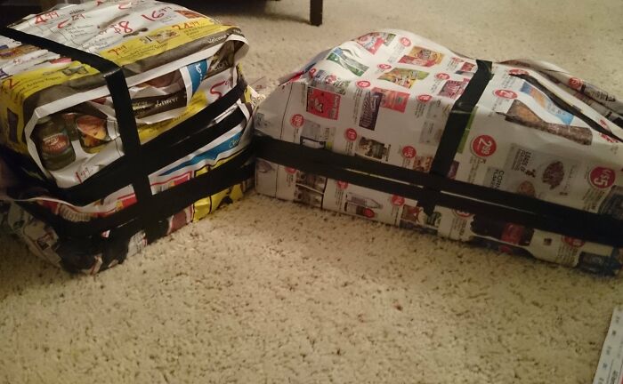 Two gifts wrapped in newspaper and secured with black tape, showcasing funny gift wraps for Christmas mischief.